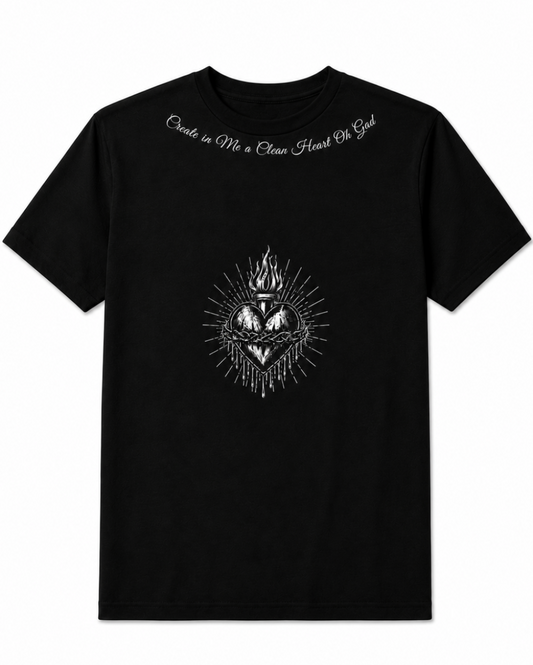 A black short-sleeve crewneck t-shirt featuring a white Sacred Heart graphic on the chest and the white cursive text 'Creede in Me a Clean Heart Or God' printed across the upper chest, displayed against a solid white background.